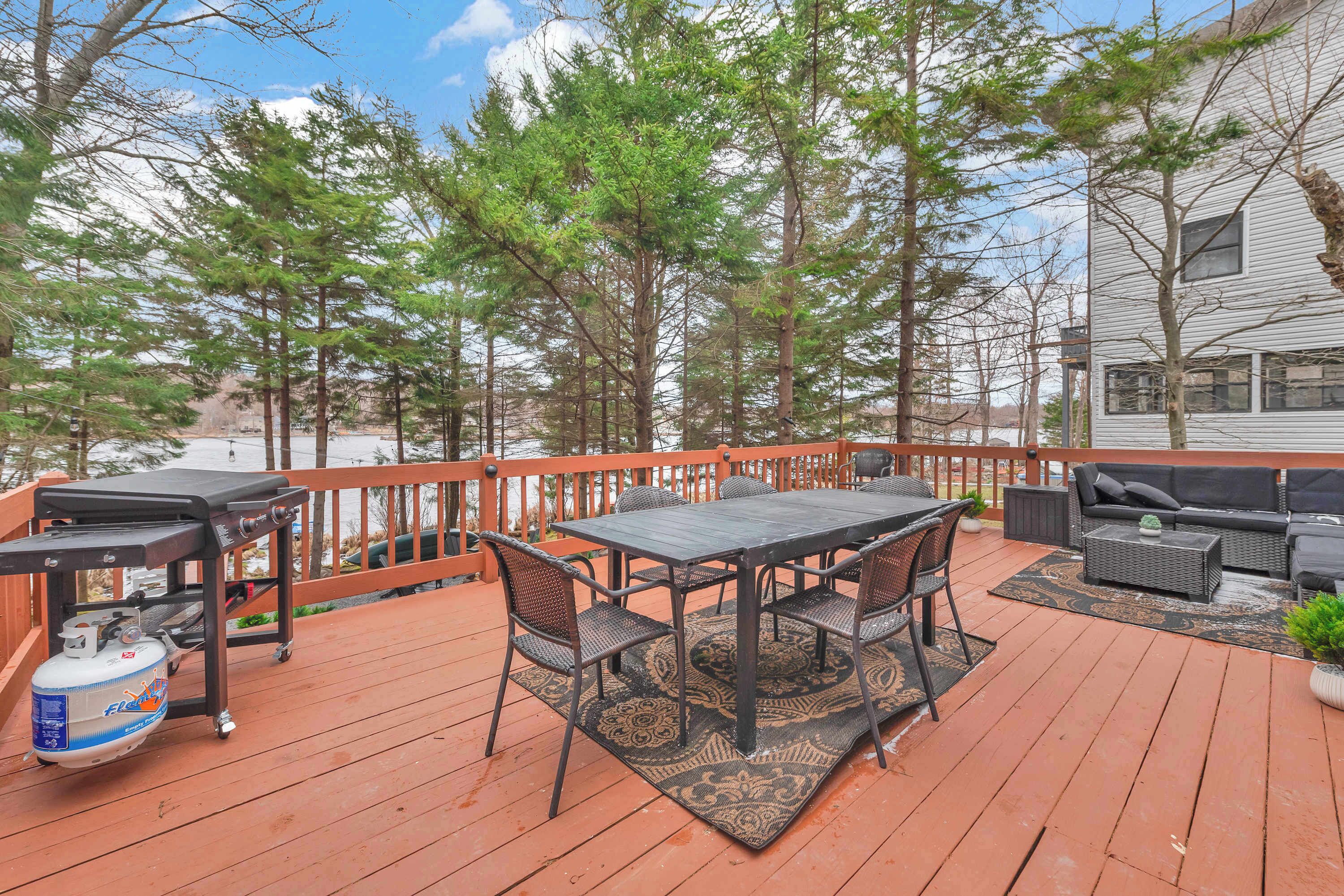A wooden deck with a table and chairs, a grill, and a barbecue.