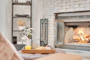 Un salon chaleureux avec une cheminée, un plateau contenant des éléments pour le petit-déjeuner et une bibliothèque.