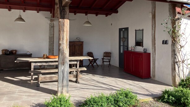 A covered patio with a tiled roof, wooden furniture, and a red cabinet. - Room at the foot of the Rhune (Sare)