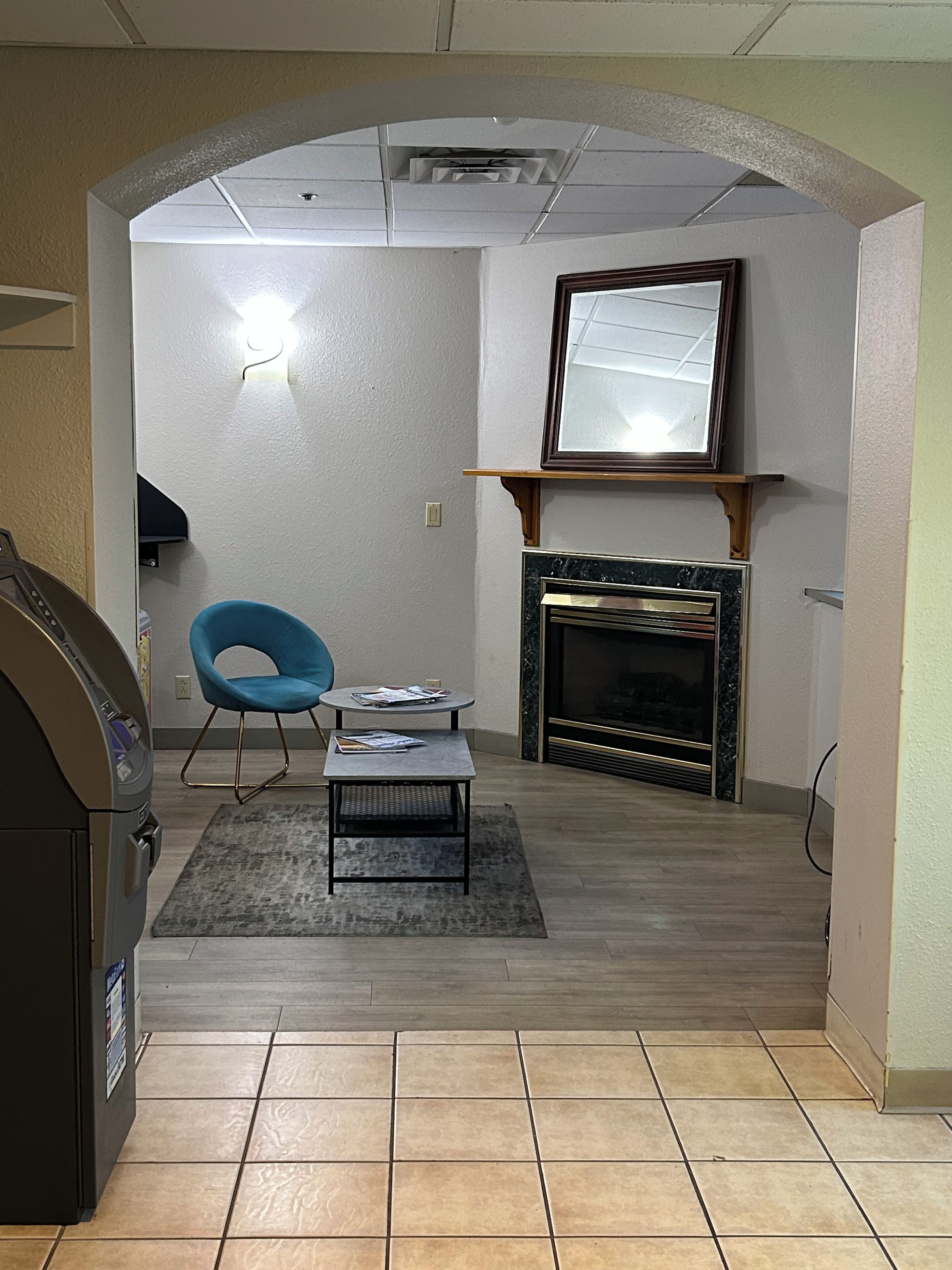 A living room with a blue chair, a small table, a fireplace, and a television.