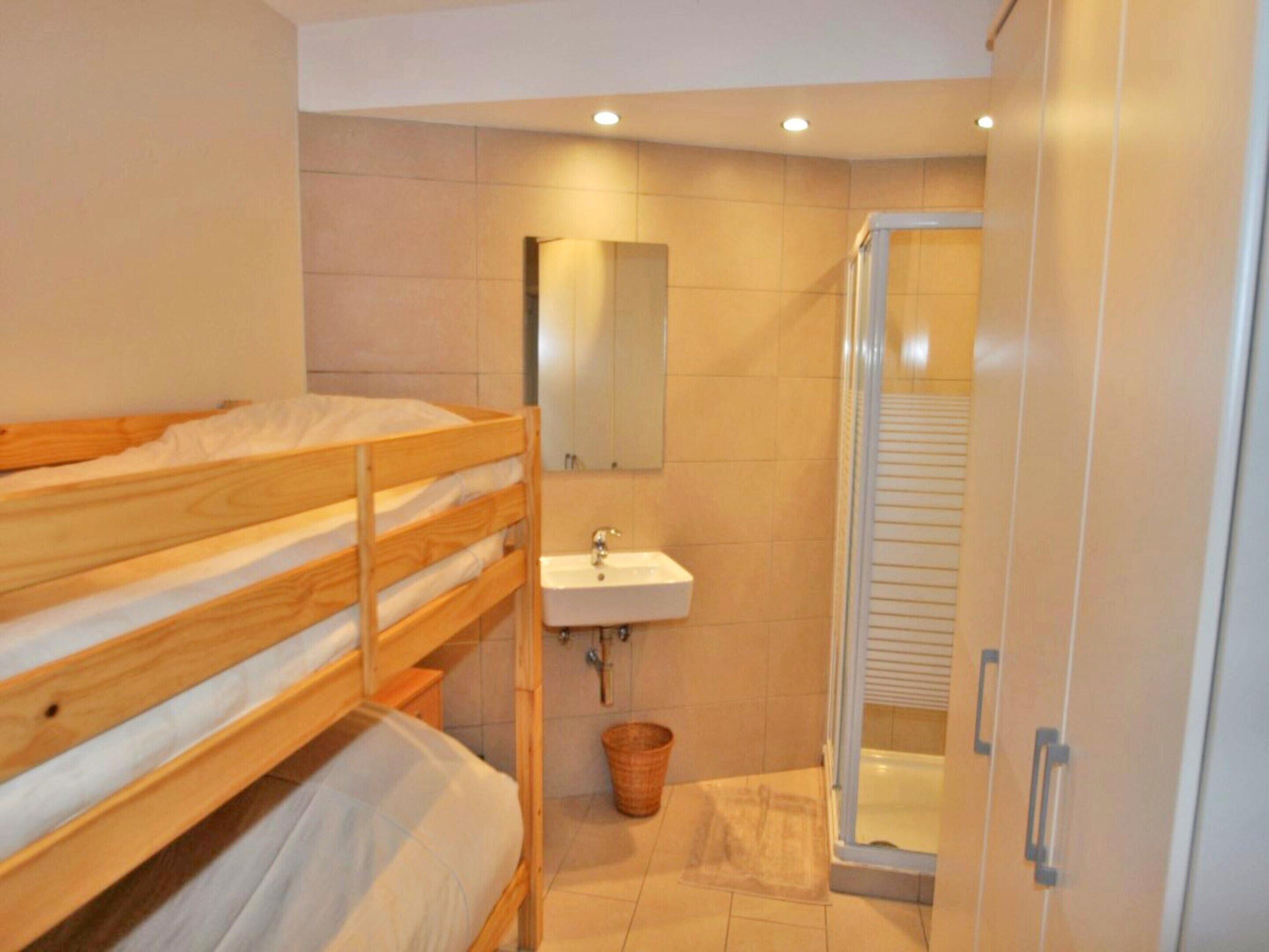 Een stapelbed, een wastafel en een douche in een badkamer.