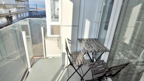 A balcony with a glass railing, a small table, and two chairs. - Apartment in Knokke Near Albertstrand Beach (Knokke-Heist)