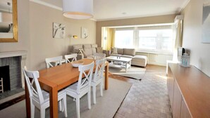 A modern living room with a dining area, a sofa set, and a fireplace. - Apartment in Knokke Near Albertstrand Beach (Knokke-Heist)
