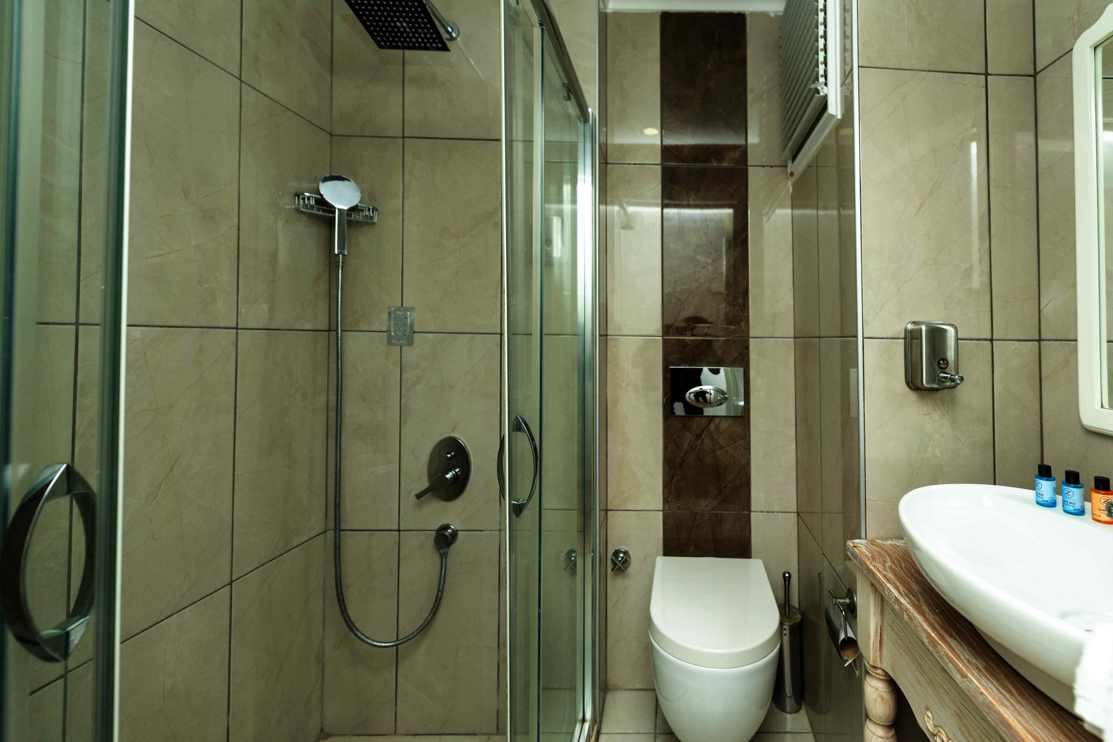 Ein modernes Badezimmer mit einer Duschkabine aus Glas, einer weißen Toilette und einer Marmorarbeitsplatte mit Toilettenartikeln.