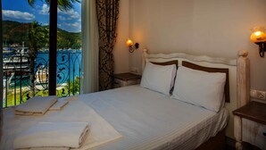 A hotel room with a large bed, two bedside tables, a view of a marina, and a balcony with a railing. - Cennet Life Boutique Hotel (Fethiye)
