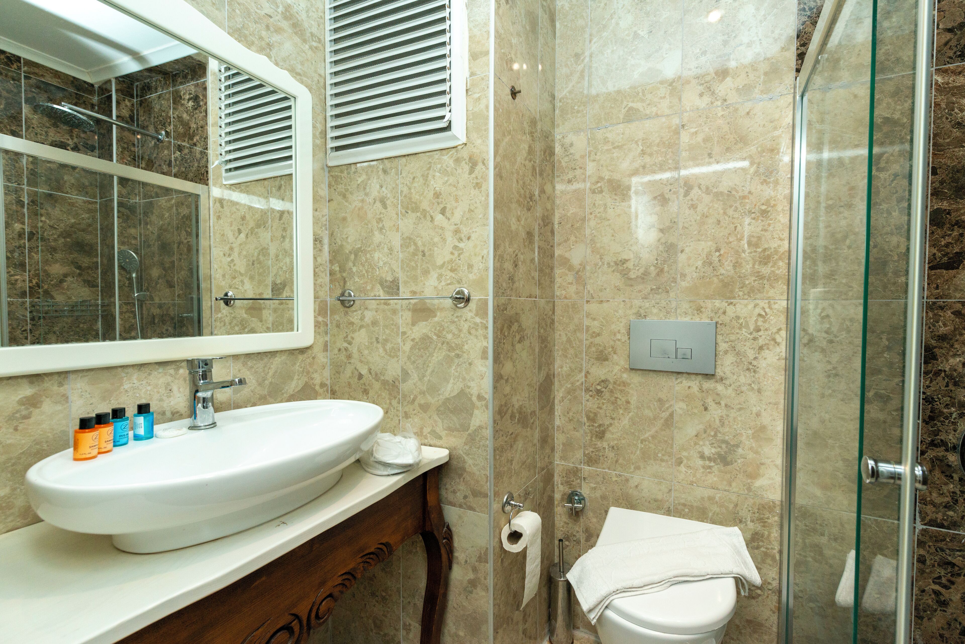 A bathroom with a large sink, mirror, and shower.