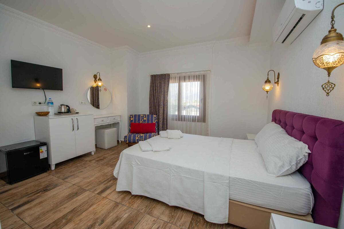 A hotel room with a bed, a desk, a chair, a television, and a window with curtains.