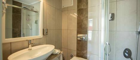Een badkamer met een groot wastafel, spiegel en douche.