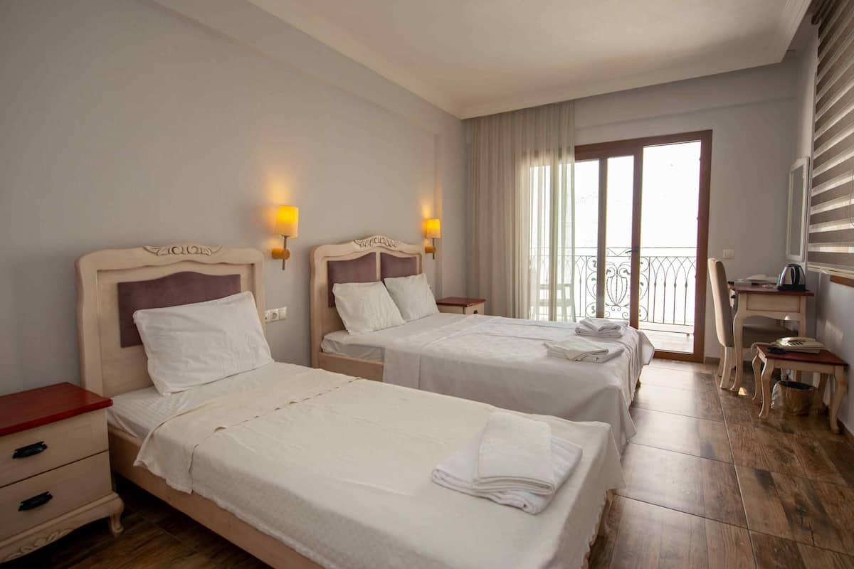 A hotel room with two beds, a desk, a chair, and a window with a view.