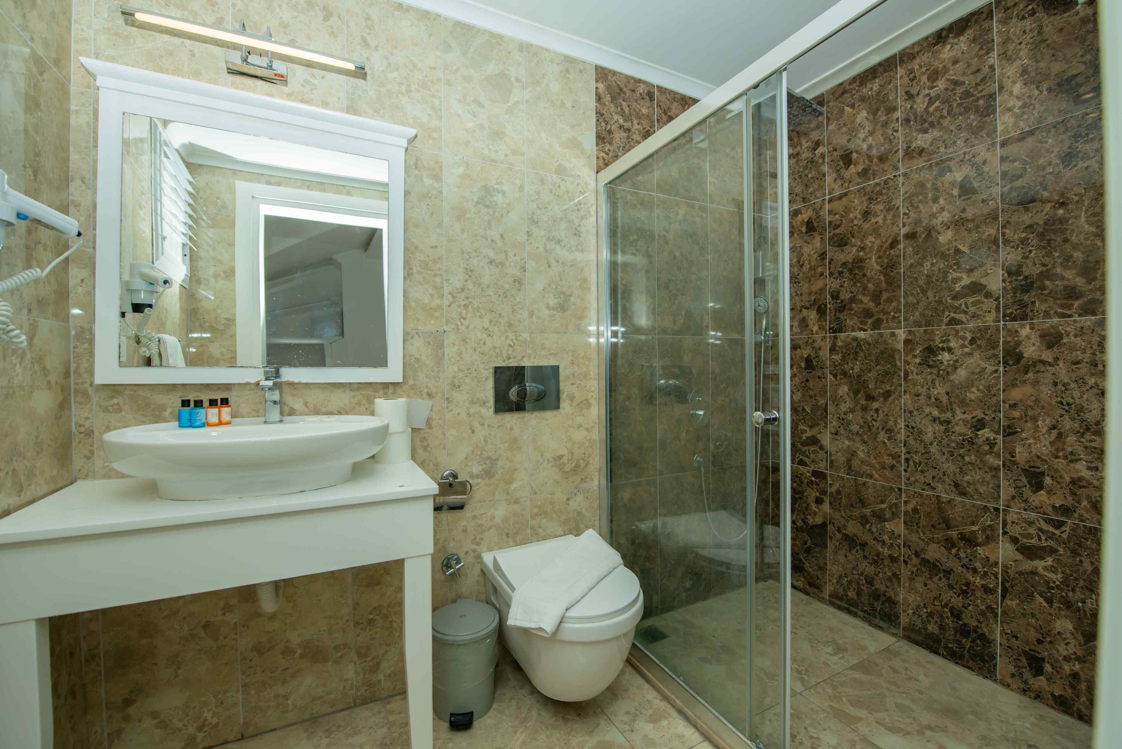 A bathroom with a white sink, mirror, and a glass shower enclosure.