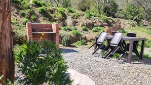 Un patio con una chimenea de ladrillo, mobiliario exterior y un pequeño árbol.