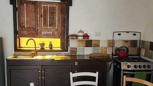 Una cocina con un armario de madera, un lavamanos, una estufa y una mesa con mantel estampado.