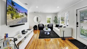 Un salon moderne avec un téléviseur à écran plat, un miroir rond, une table basse et un canapé.