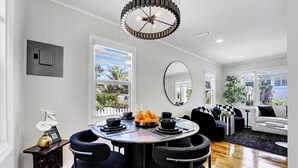 Un espace de salle à manger moderne avec une table ronde, des chaises noires et un lustre.