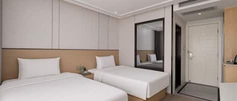 A hotel room with two beds, a large mirror, and a door leading to the outside.