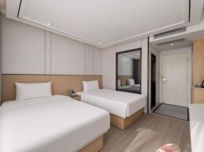 Una habitación de hotel con dos camas, un espejo grande y una puerta que da al exterior.