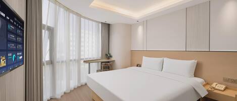 Una habitación de hotel con una cama grande, una mesita de noche con un teléfono, un espejo y un televisor en la pared.