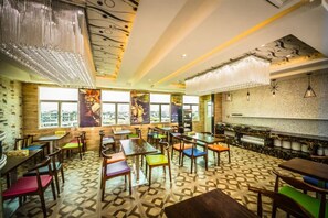 Um restaurante com piso estampado, mesas e cadeiras de madeira, e um espaço de bar com parede decorada.