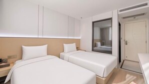 Ein Hotelzimmer mit zwei Betten, einem Nachttisch, einem Spiegel und einer Tür.