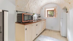 Et køkken med en stenbuet indgang, mikroovn, vask og køleskab.