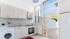 Una cocina moderna con lavadora, horno y un tapete rojo estampado.