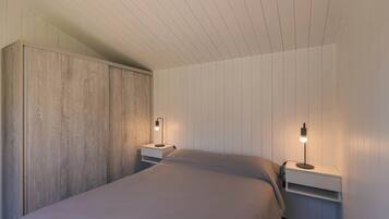 Een slaapkamer met een bed, twee nachtkastjes en een houten garderobe.