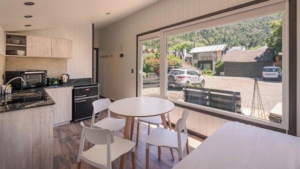 A modern kitchen with a dining area, large windows, and a view of the surrounding area. - Tiny House (San Martin de los Andes)
