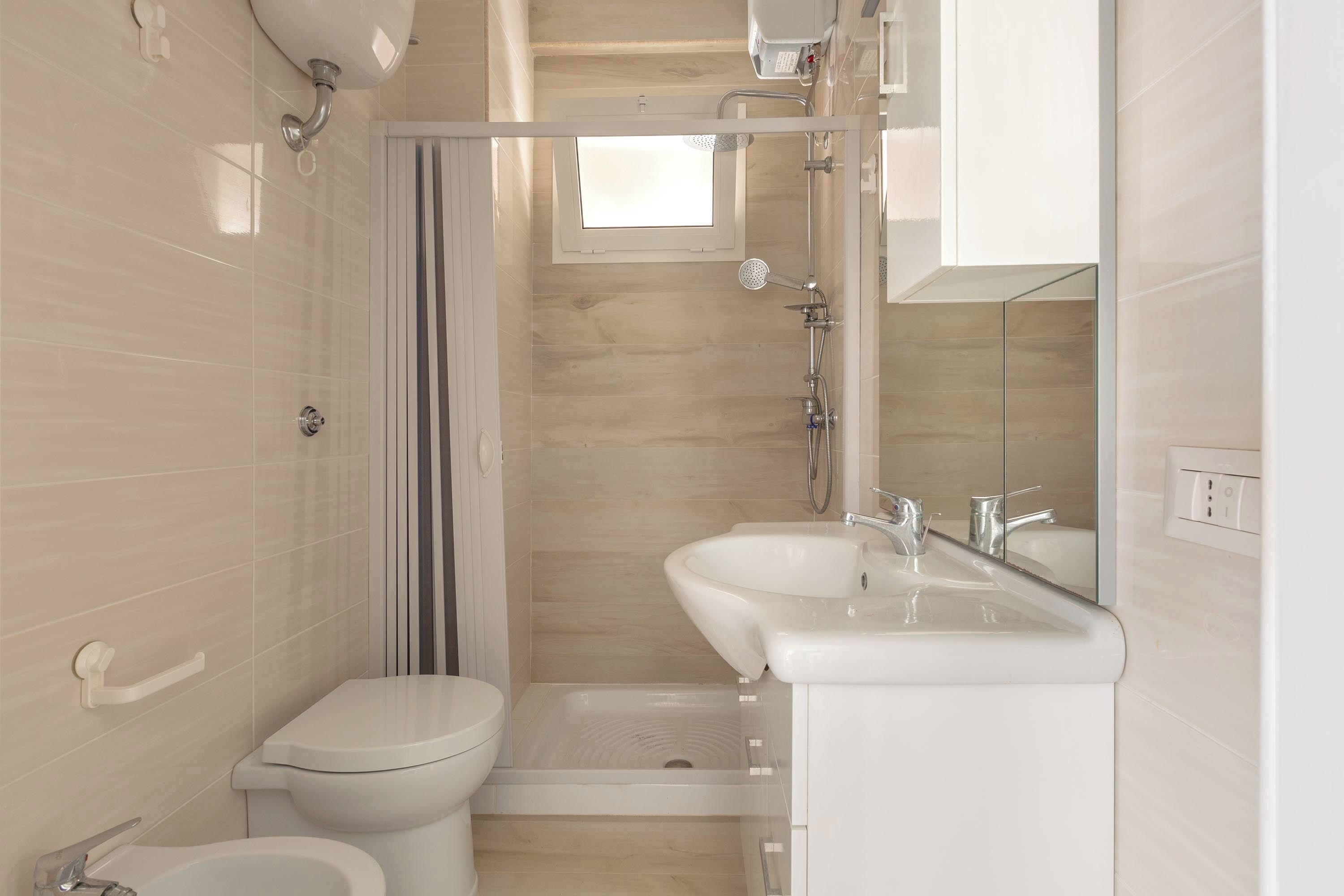 A modern bathroom with a toilet, bidet, shower, and sink.
