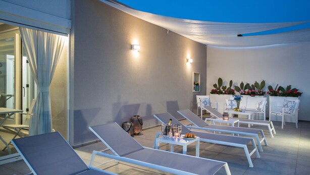 An outdoor lounge area with sun loungers, a table with drinks, and a cactus plant display. - Palazzo Perla - Junior Suite con Balcone (Gallipoli)