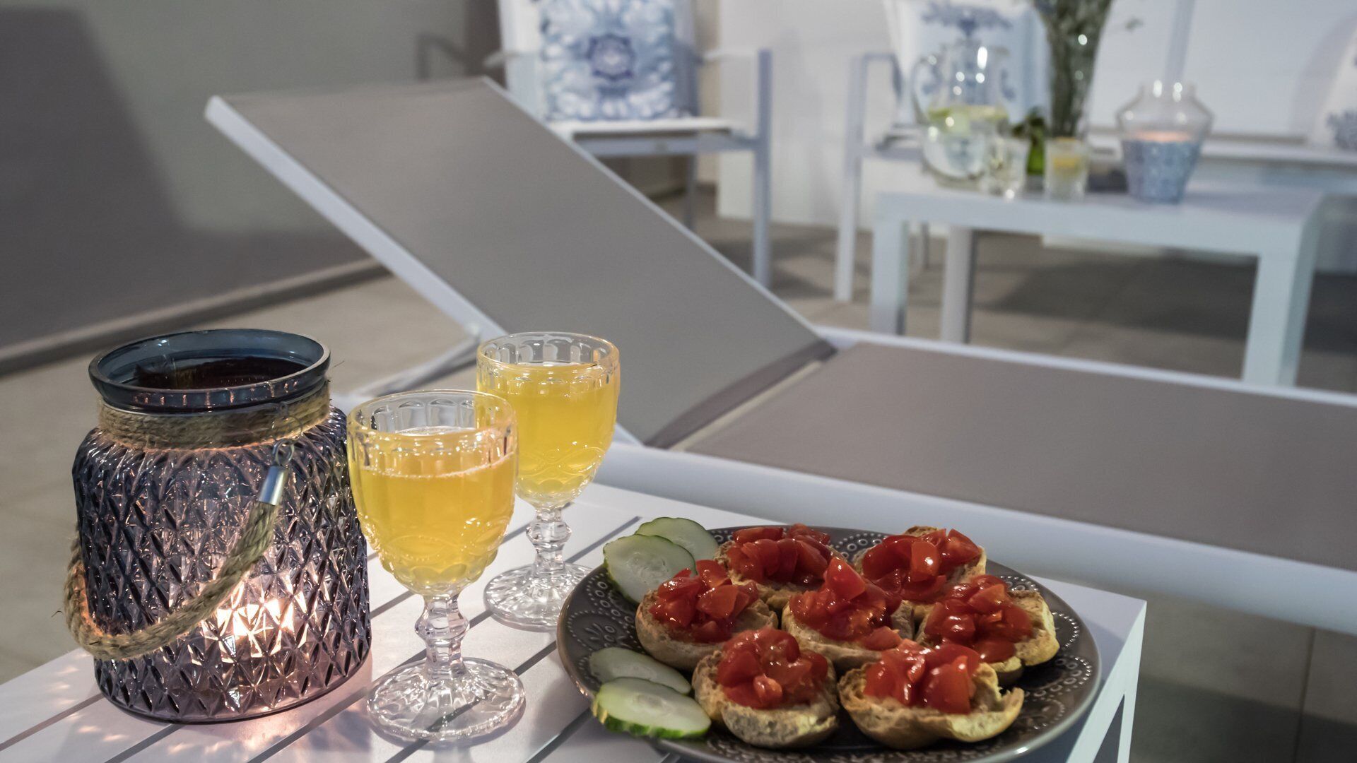 Una mesa con una fuente de bruschetta, un vaso de jugo de naranja y un candelabro.