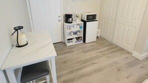 A small, clean room with a white desk, chair, and a microwave on a white cabinet. There is a white door and a closet with a white door. - Charming 1 bed suite with AC and WiFi in Lakeland (Lakeland)