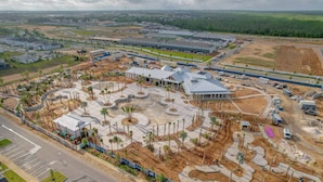Vue aérienne d’un vaste complexe immobilier commercial comprenant plusieurs bâtiments, des espaces paysagers et un parking.