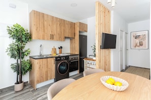 A modern kitchen with wooden cabinets, a built-in oven, and a washing machine.
