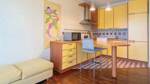 Cocina compacta con gabinetes amarillos, microondas, tostadora y una mesa de comedor con sillas.