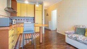 Una cocina compacta con gabinetes amarillos, una mesa de comedor de madera y una silla azul.