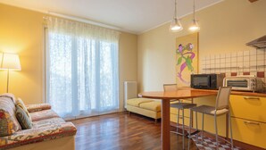 Una sala de estar acogedora con un sofá, una mesa de comedor y una zona de cocina con microondas y tostadora.