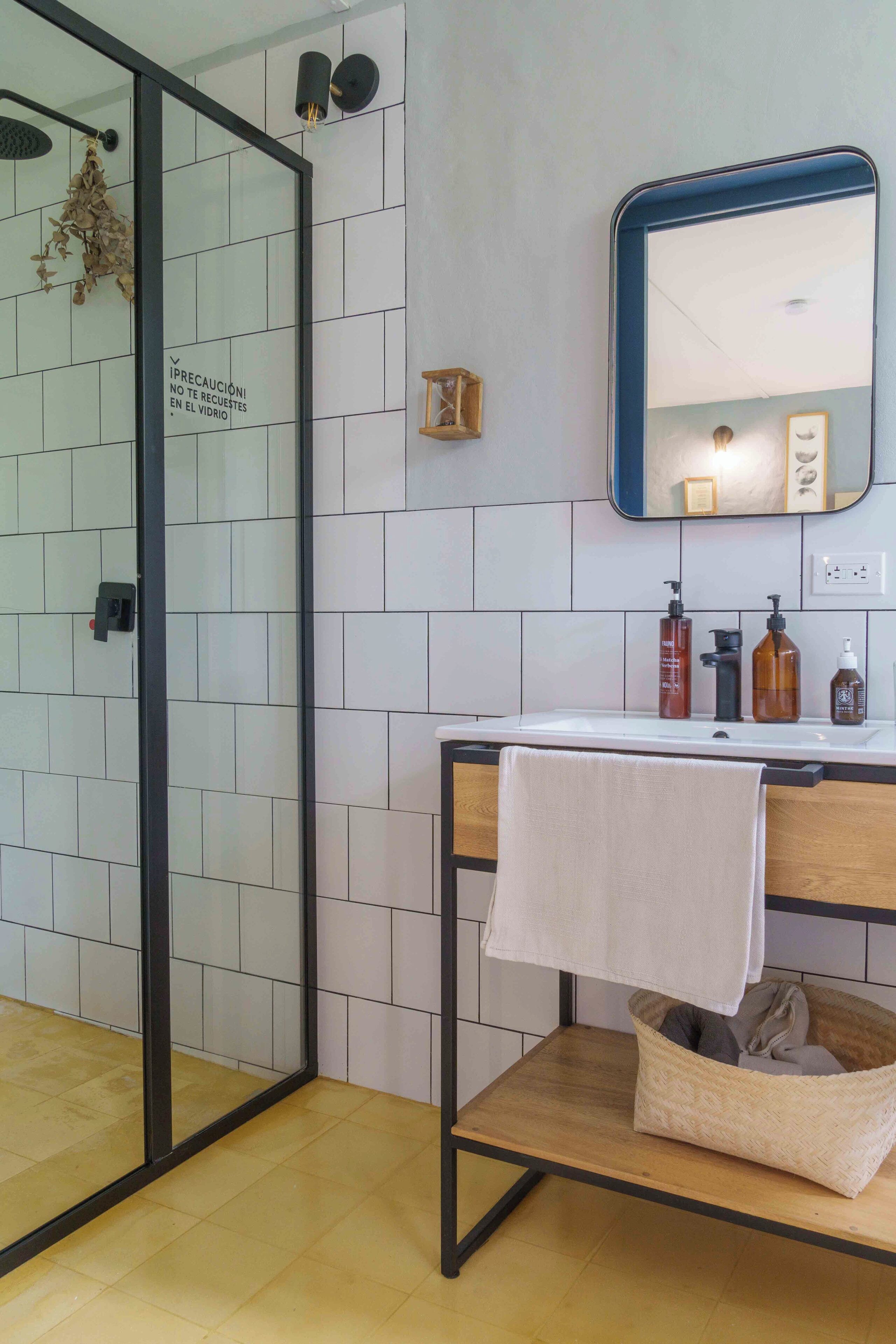 A bathroom with a glass shower enclosure, a wooden vanity with a towel, and a mirror above the sink.