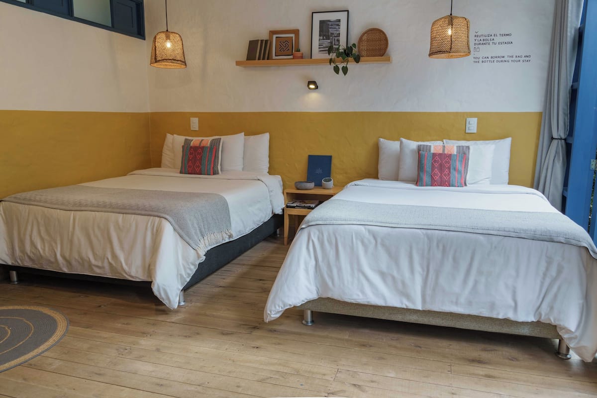 Ett hotellrum med två sängar, trägolv och en vägghylla med dekorativa föremål.