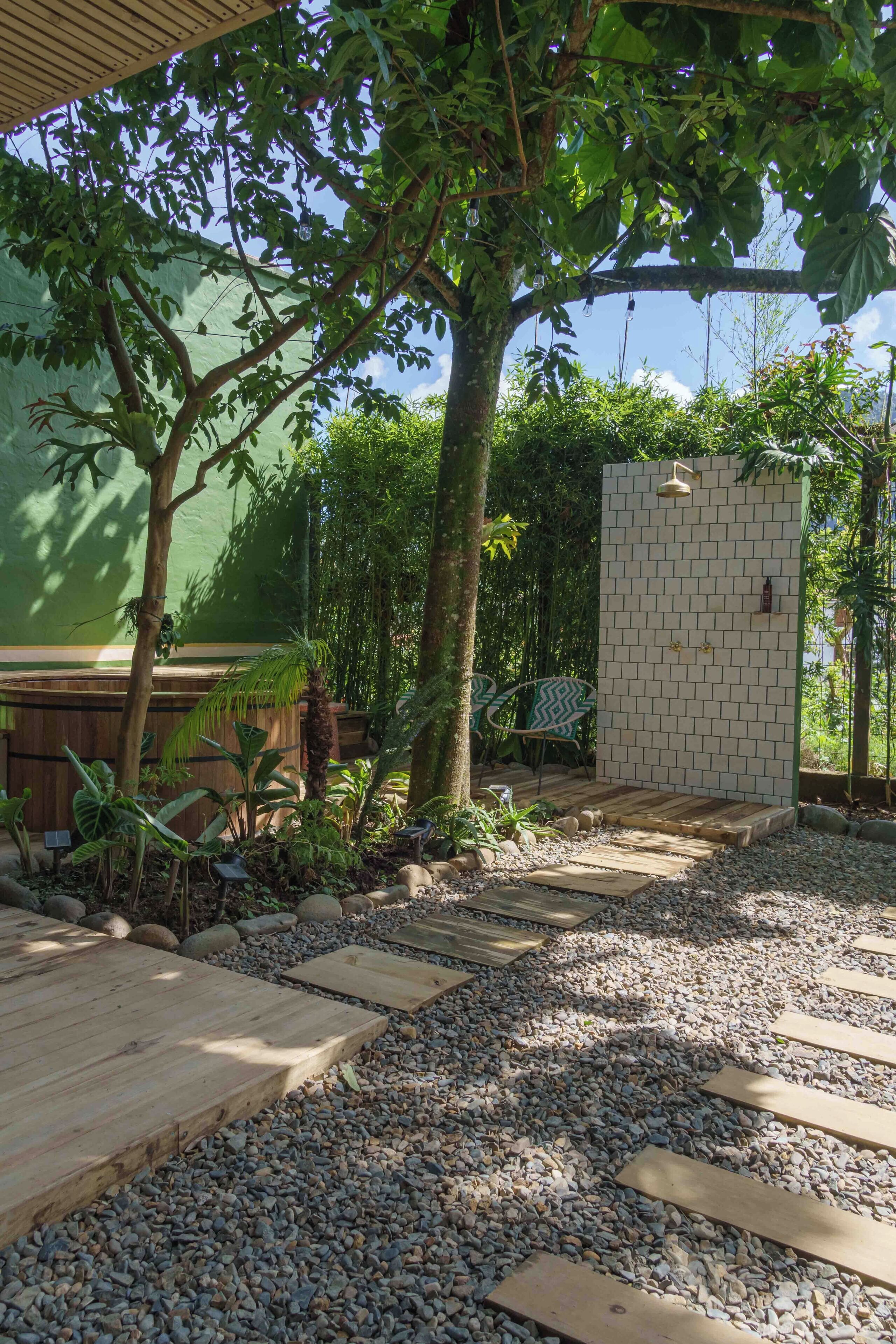 Un espacio al aire libre cubierto con una terraza de madera, un muro de ladrillo y diversas plantas.