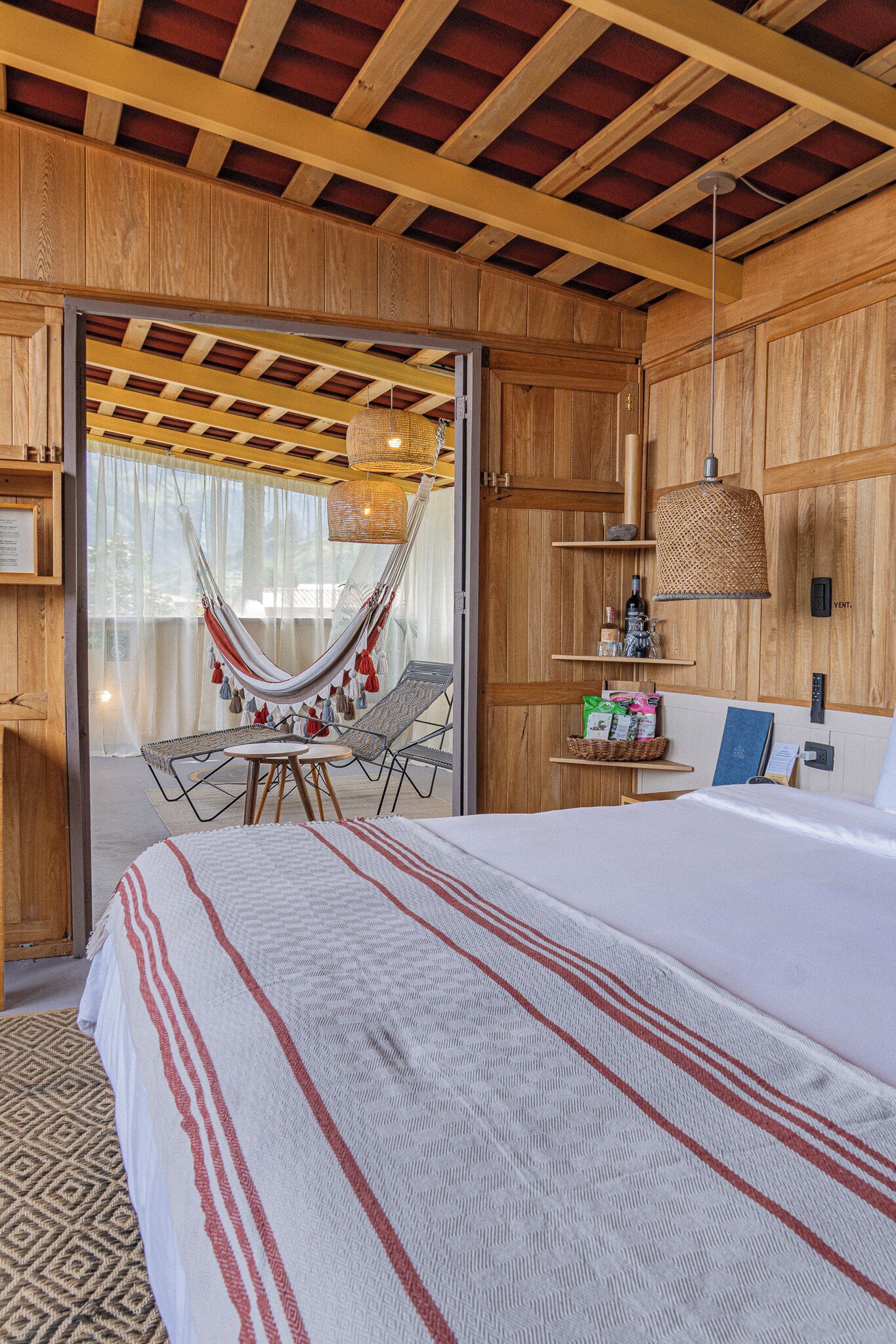 Una habitación con una cama, una hamaca, una mesa y un estante con objetos.