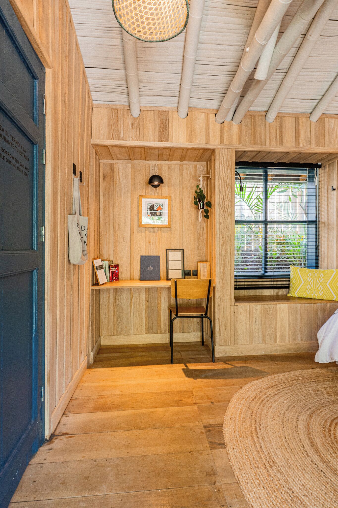 Ein Zimmer mit einem Holztisch, einem Stuhl und einem Fenster mit Jalousien.