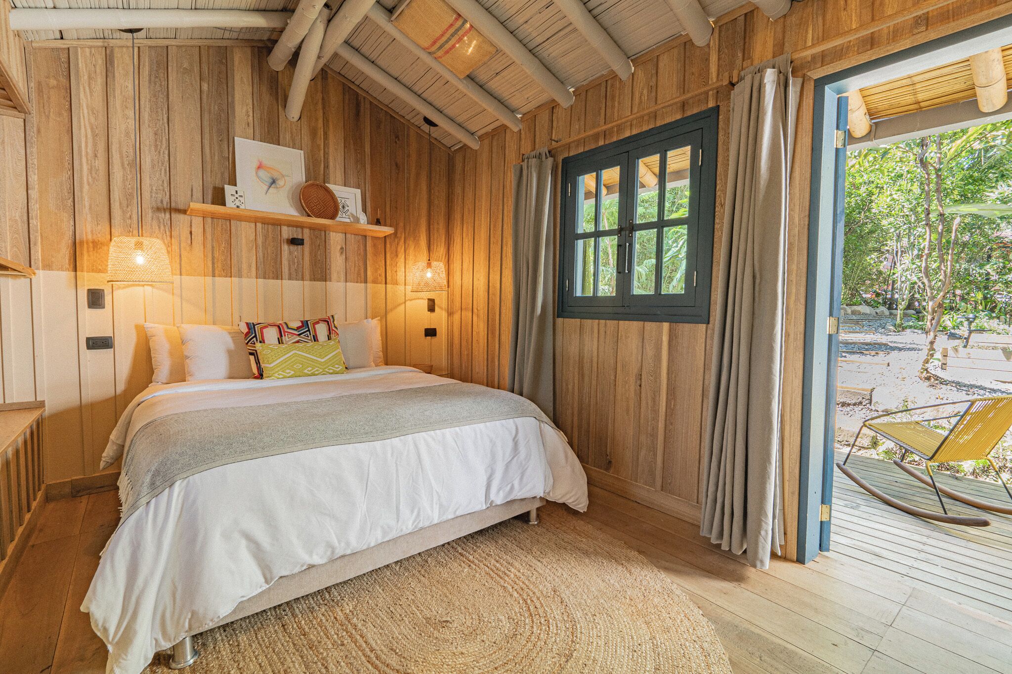 A wooden room with a bed, a window, and a view of the outdoors.