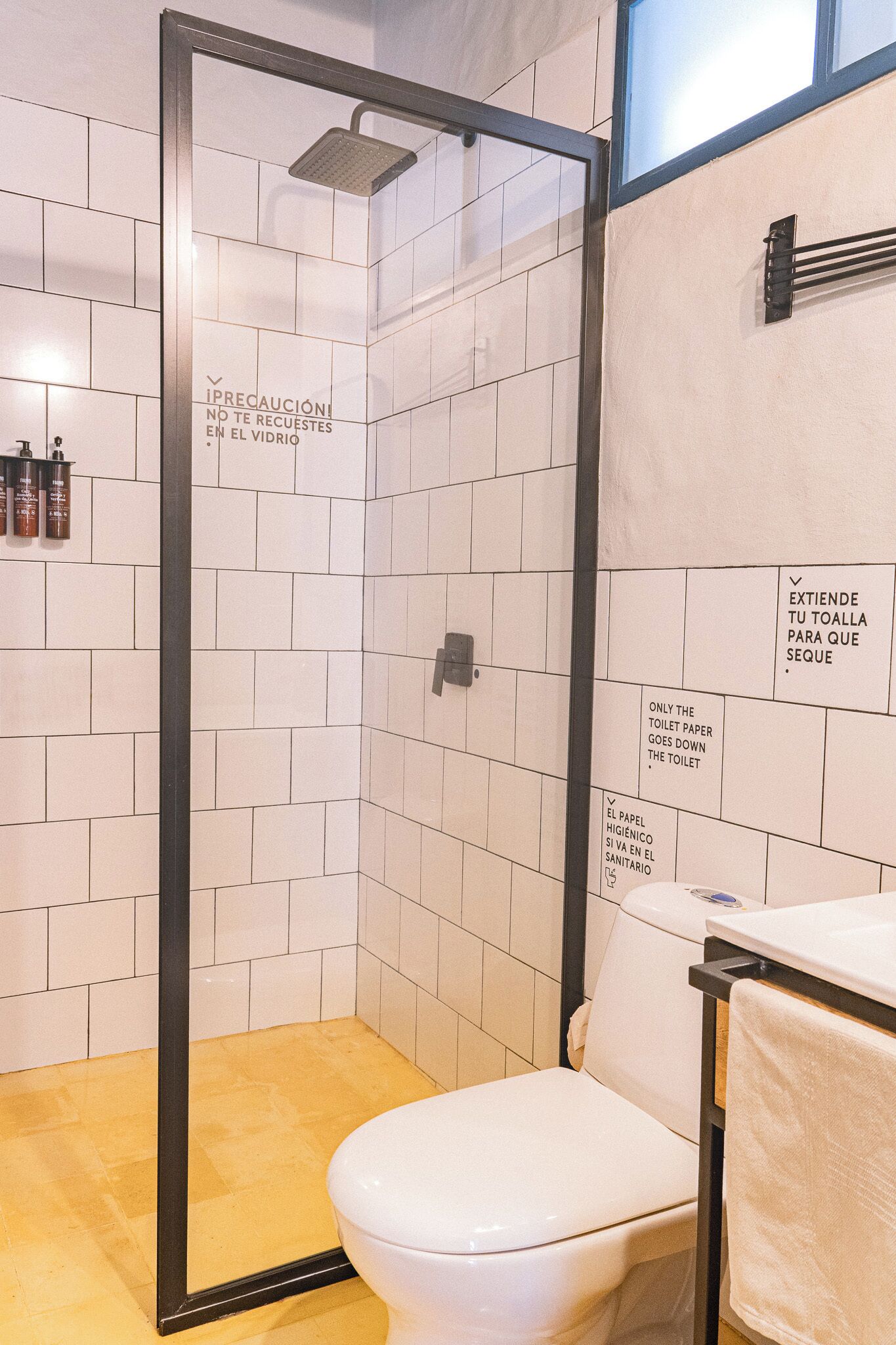 Une salle de bain avec des toilettes blanches, un espace douche et des murs carrelés.
