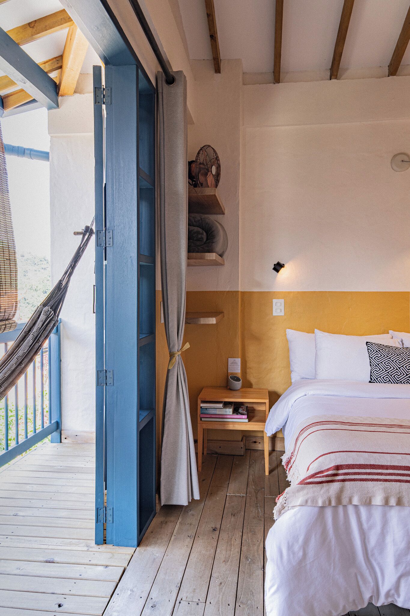 Une chambre avec un lit, une table de chevet et un hamac.