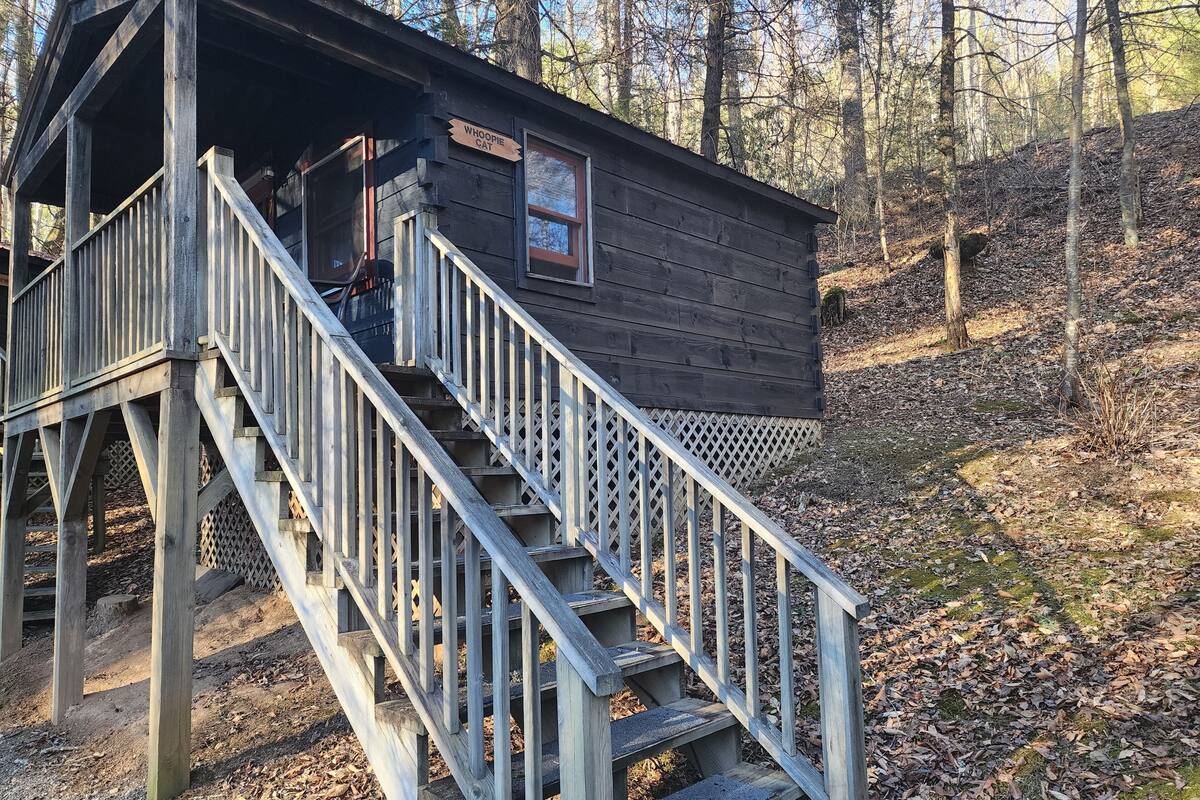 A wooden cabin with a staircase leading to a porch.