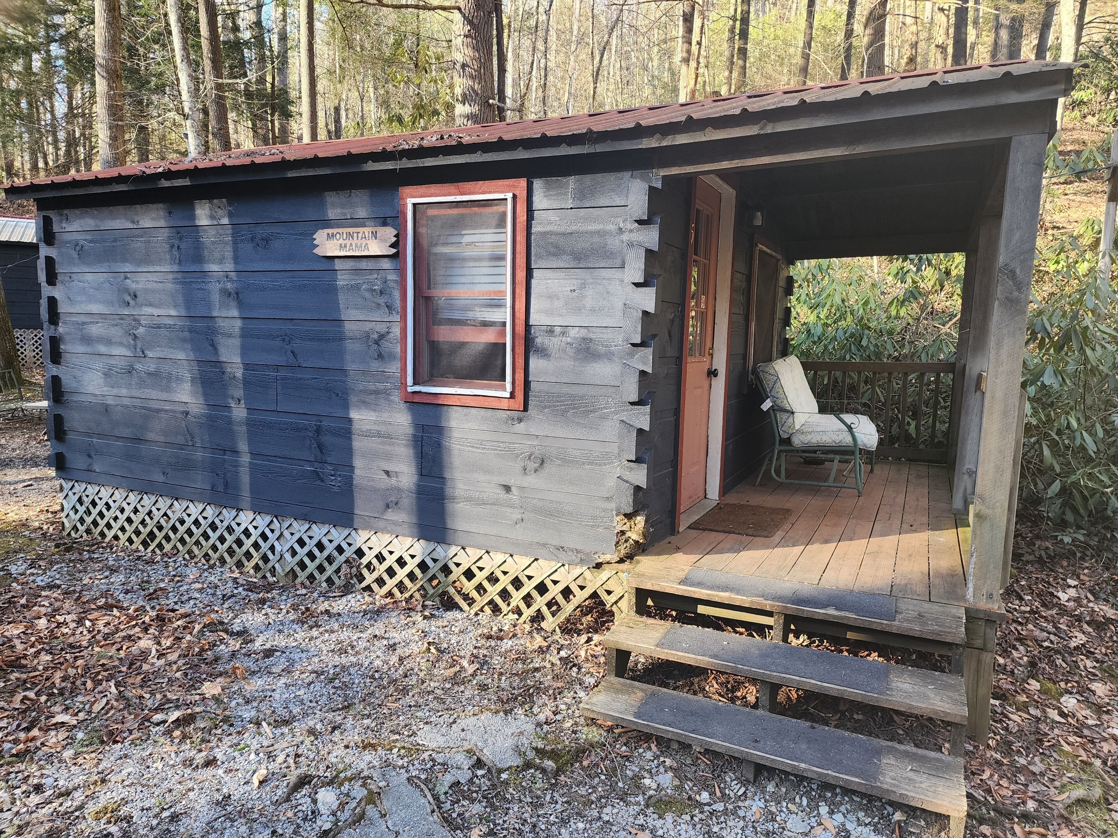 Une petite cabane en bois avec une véranda, une enseigne sur laquelle on peut lire « MOUNTAIN MAMA », et une chaise à l’extérieur.