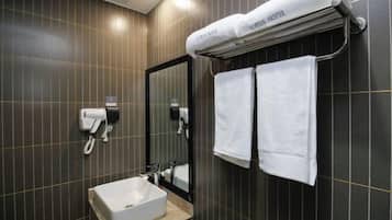 A modern bathroom with dark tiled walls, a white sink, a mirror, and a towel rack with a towel labeled "UPPLUS HOTEL".