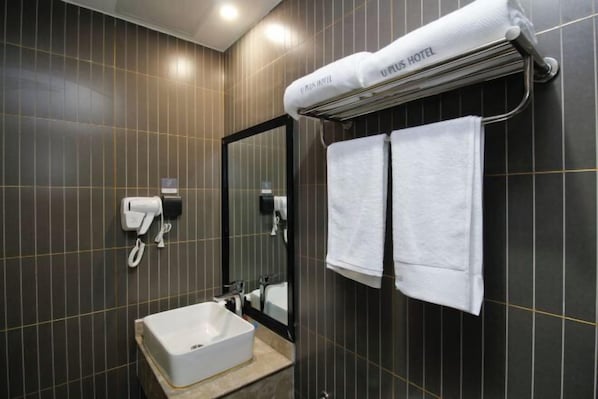 A modern bathroom with dark tiled walls, a white sink, a mirror, and a towel rack with a towel labeled "UPPLUS HOTEL". - Shankee Hotel (Xin'an Hangzhou Road) (Xin'an)
