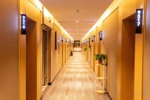 A hotel hallway with doors numbered 9518 and 9517, carpeted floors, and a plant on the right side. - Shankee Hotel (Xin'an Hangzhou Road) (Xin'an)