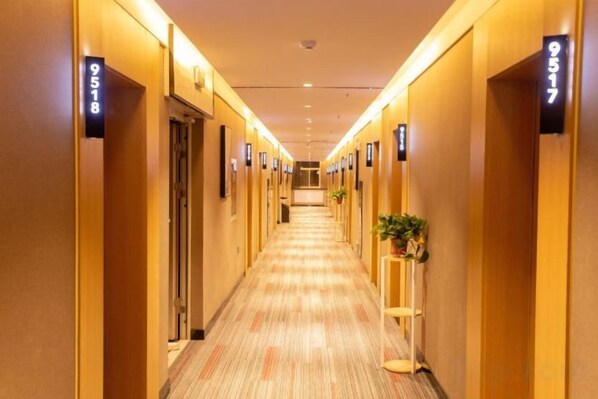 A hotel hallway with doors numbered 9518 and 9517, carpeted floors, and a plant on the right side. - Shankee Hotel (Xin'an Hangzhou Road) (Xin'an)